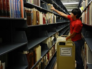 Uribe assists with a project to consolidate space, shifting books in our secure stacks area